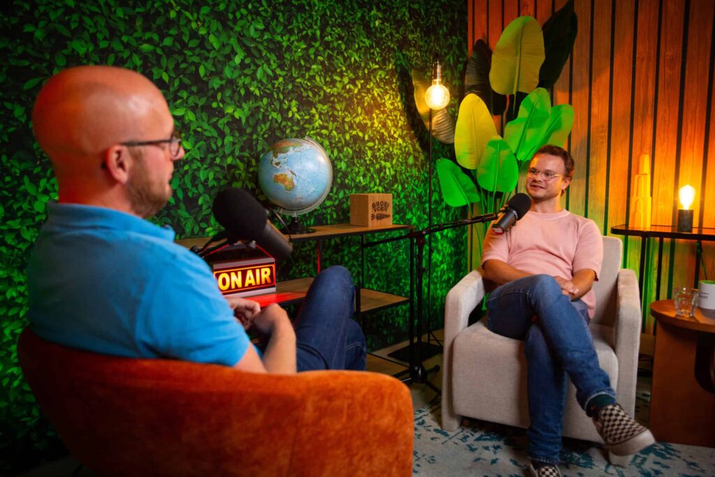 Twee mannen in gesprek tijdens de Groeivoer Podcast, zittend in een kleurrijke studio met microfoons en sfeerverlichting.