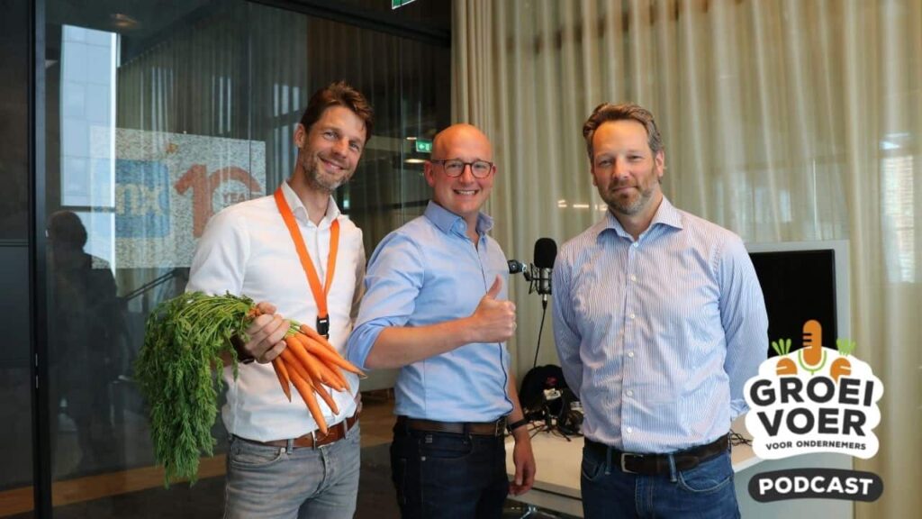 Drie mannen poseren in een podcaststudio voor aflevering 46 van de Groeivoer podcast, waarvan één een bos wortels vasthoudt.