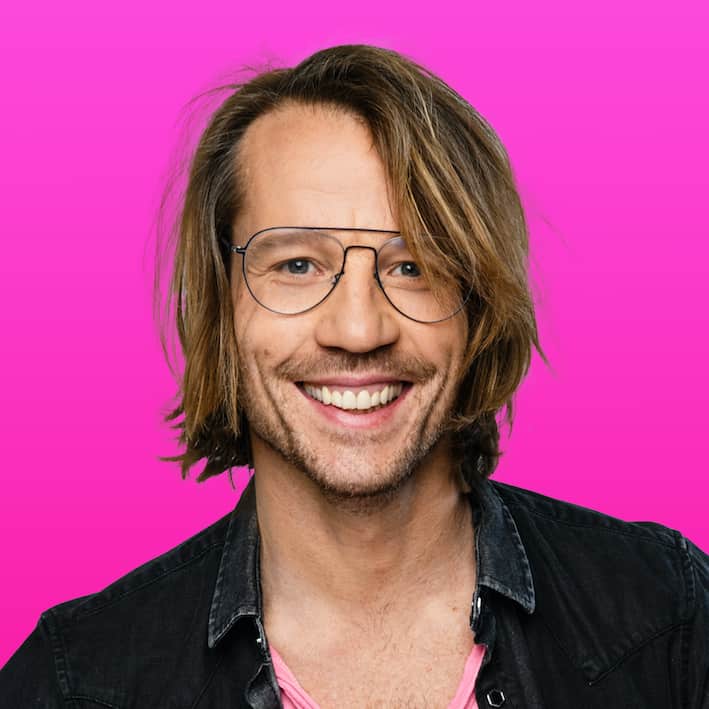 Giel Beelen lacht naar de camera voor een felroze achtergrond tijdens de Groeivoer Podcast voor ondernemers.
