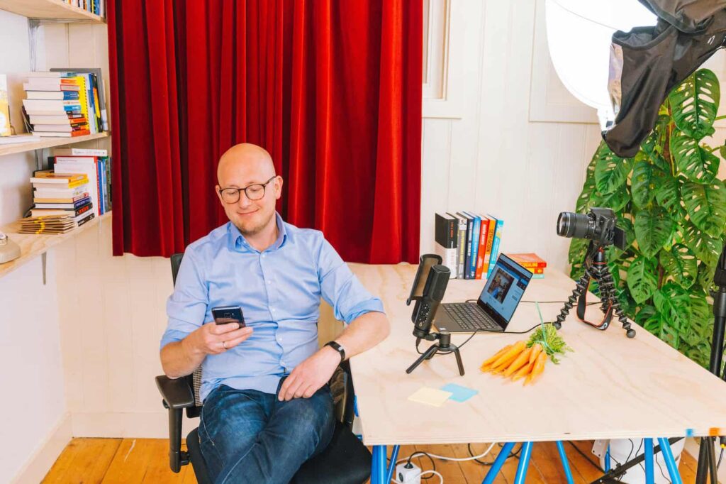 Gerhard te Velde van Groeivoer zit ontspannen aan een bureau met opnameapparatuur, boeken en een bos wortels.