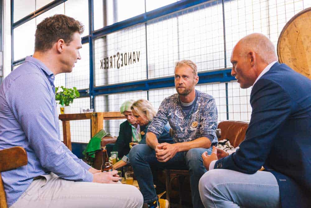 Drie mannen in gesprek op een informele netwerkbijeenkomst bij VANDERSTEEK.