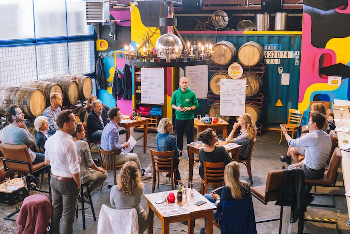 Een groep ondernemers volgt een interactieve workshop over het bouwen van een dreamteam in een kleurrijke, industriële ruimte.